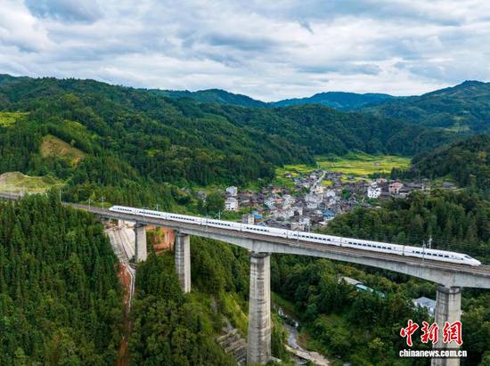 图为一列动车组列车从贵州省从江县往洞镇朝利侗寨旁疾驰而过。（无人机照片）吴德军 摄