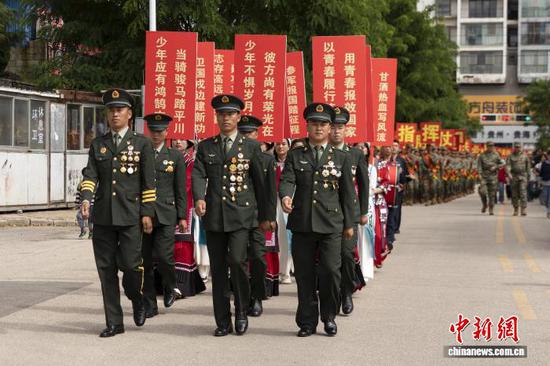 图为9月13日，威宁彝族回族苗族自治县退伍功臣代表带领入伍新兵队伍巡游。赵庆能 摄