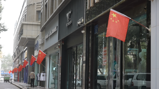 商户门前挂起鲜艳的国旗。