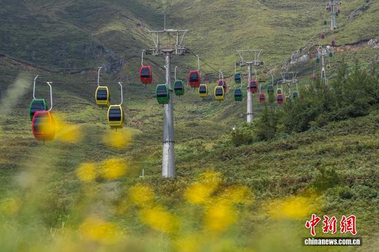 图为游客在贵州省毕节市赫章县韭菜坪景区乘坐缆车。