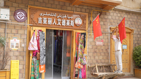 如则托合提·阿卜杜哈力克正在自家门前挂国旗。