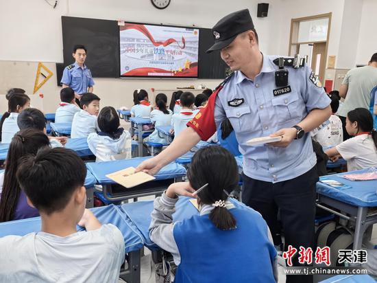 图为民警在教室为学生发放笔记本，鼓励同学们认真学习。（北京铁路公安局天津公安处供图）