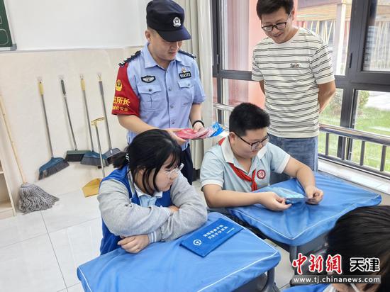 图为民警在教室给学生发放法治宣传手册，同学们认真观看。（北京铁路公安局天津公安处供图）