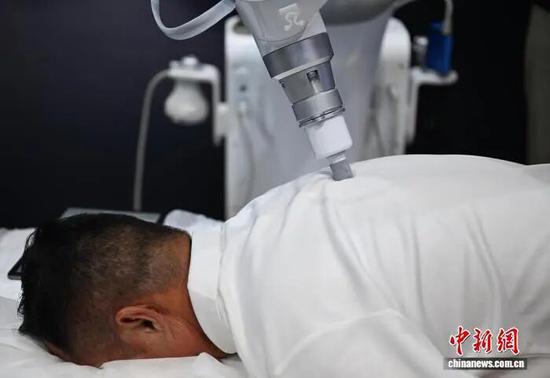 中医按摩机器人为参观者按摩。王刚 摄 中医按摩机器人为参观者按摩。王刚 摄