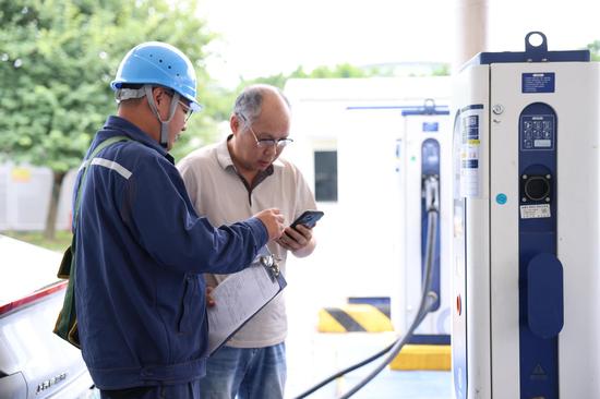 在柳州鹿山综合能源站内,工作人员贴心为客户介绍充电APP功能。陆雯 摄 在柳州鹿山综合能源站内,工作人员贴心为客户介绍充电APP功能。陆雯 摄