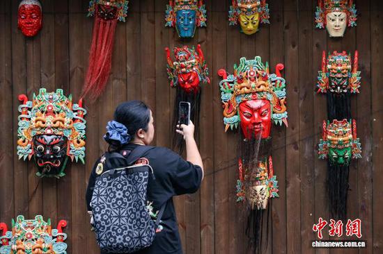 10月2日，游客在云山屯拍摄安顺地戏面具。中新社记者 瞿宏伦 摄