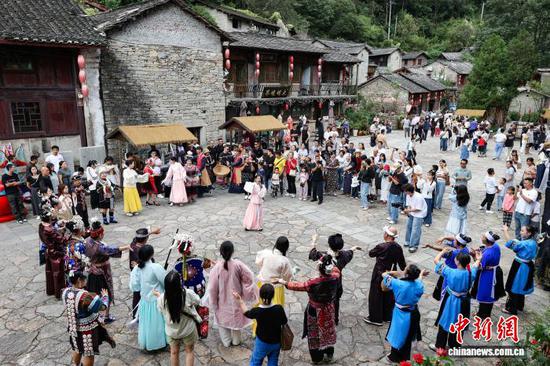 10月2日，游客和表演者在云山屯互动。中新社记者 瞿宏伦 摄