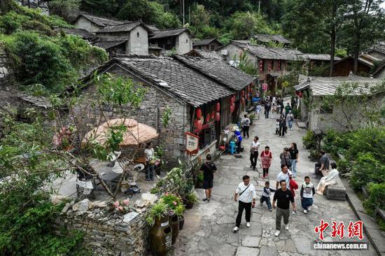 10月2日，游客在云山屯游览。云山屯位于贵州省安顺市西秀区云峰屯堡景区内，距今已有600年历史。国庆、中秋双节期间，云山屯依托保存完好的明朝建筑、传统的民俗风情和深厚的历史文化底蕴，举办古风剧游、迎宾入屯仪式等沉浸式体验项目，吸引不少民众前来感受六百年大明遗韵。（无人机照片）中新社记者 瞿宏伦 摄