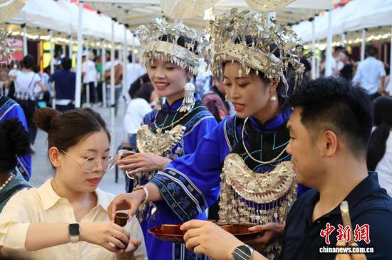 图为10月1日，游客在三都水族自治县万户水寨品尝水族长桌宴，水族妇女向游客敬酒。记者 刘美伶 摄