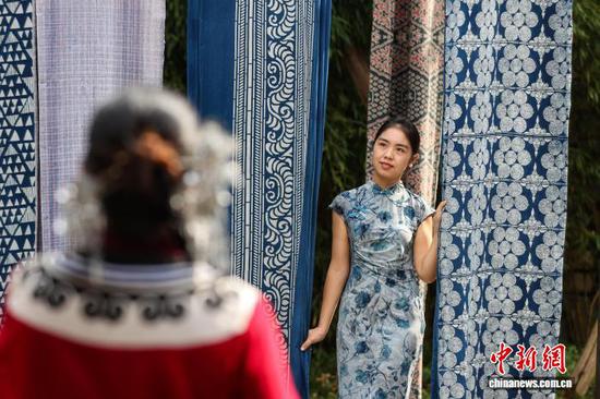 10月4日，游客穿着旗袍在乌江寨蜡染体验区拍照。中新社记者 瞿宏伦 摄