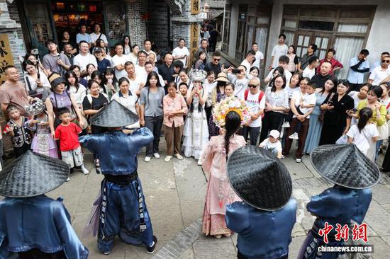 10月4日，乌江寨的演员和游客一起互动被围观。中新社记者 瞿宏伦 摄