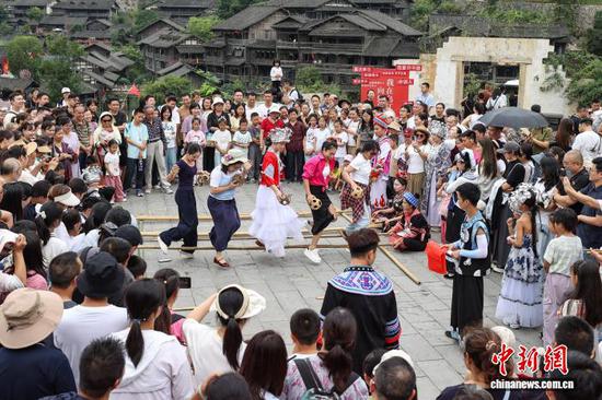 10月4日，游客在乌江寨体验竹竿舞和篾鸡蛋投掷。中新社记者 瞿宏伦 摄