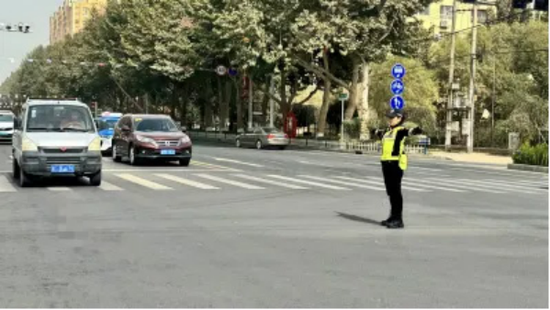 交警在路中央，挥动手势，引导车辆有序通行。