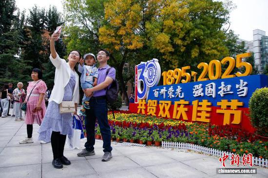 10月2日,校友在天津大学卫津路校区北洋园与建校130周年主题标识合影。 中新社记者 佟郁 摄
