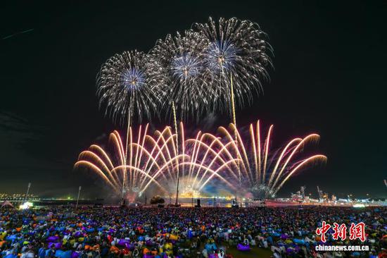 图为10月2日晚，市民和游客在天津泰达航母主题公园观看焰火秀。记者 佟郁 摄