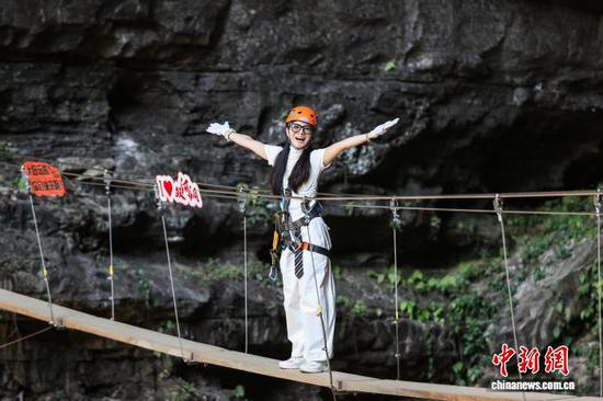 10月11日，游客在贵州省遵义市绥阳县双河洞景区“悬崖之上·侠客咖啡”项目挑战中。中新社记者 瞿宏伦 摄