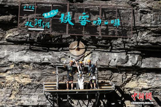 10月11日，游客在贵州省遵义市绥阳县双河洞景区“悬崖之上·侠客咖啡”项目挑战中合影。中新社记者 瞿宏伦 摄