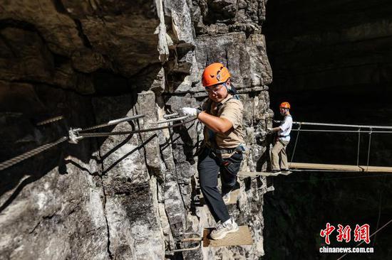 10月11日，游客在贵州省遵义市绥阳县双河洞景区“悬崖之上·侠客咖啡”项目挑战中。中新社记者 瞿宏伦 摄