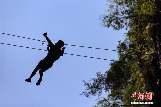10月11日，游客在贵州省遵义市绥阳县双河洞景区“悬崖之上·侠客咖啡”项目挑战中。中新社记者 瞿宏伦 摄