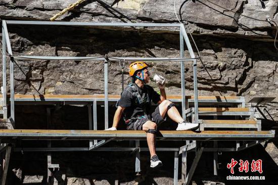 10月11日，游客在贵州省遵义市绥阳县双河洞景区“悬崖之上·侠客咖啡”项目挑战中手持道具拍照。中新社记者 瞿宏伦 摄