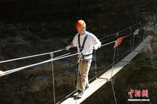 10月11日，游客在贵州省遵义市绥阳县双河洞景区“悬崖之上·侠客咖啡”项目挑战中。中新社记者 瞿宏伦 摄