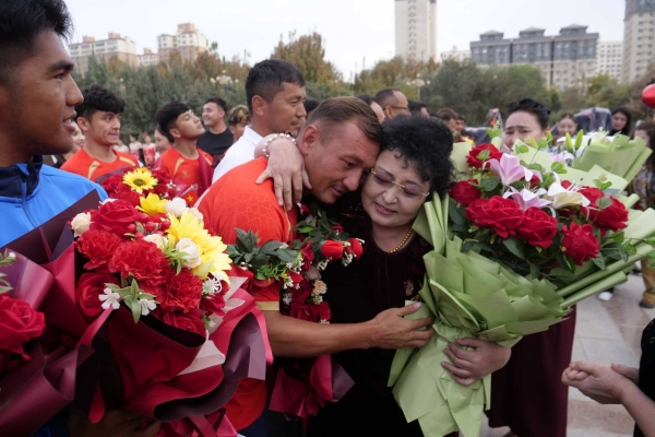 各族群众迎接载誉而归的球员,并为足球队员及教练员献上鲜花。张永亮 摄 各族群众迎接载誉而归的球员,并为足球队员及教练员献上鲜花。张永亮 摄