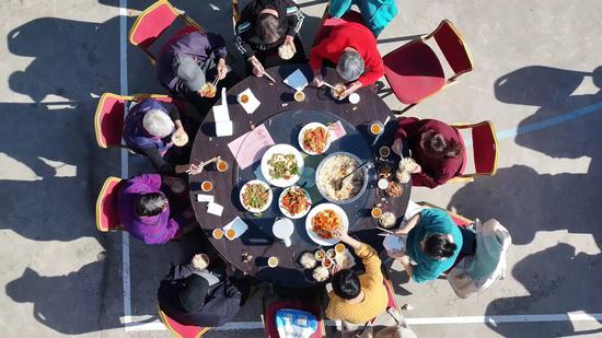 饭桌上，村民们你一言我一语的分享着家常趣事，欢快的笑声此起彼伏。杨涛 摄