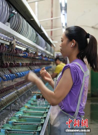 10月16日，走进贵州省毕节市赫章县野马川工业园区，贵州丝路兴蚕纺织有限公司的缫丝车间里机器轰鸣，数十名员工在各自负责的机器间游走，有条不紊地将蚕茧转化为丝线。“兴蚕缫丝、带动一方。”该公司相关负责人介绍，公司成立于2019年，通过“公司+合作社+基地＋农户”的模式，打通蚕桑种植、蚕茧缫丝、蚕丝被加工，实现了从种植到产品产业链转化，带动当地80多人就业，助农增收成效明显。图为10月16日，工人在车间里进行缫丝工作。石小杰 摄