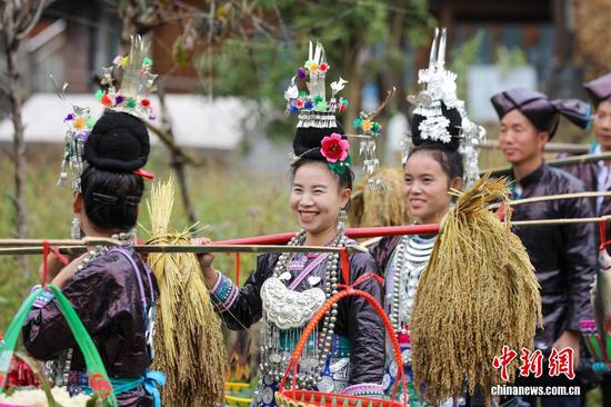10月18日，身着盛装的黄岗村村民肩挑农作物，喜庆丰收。