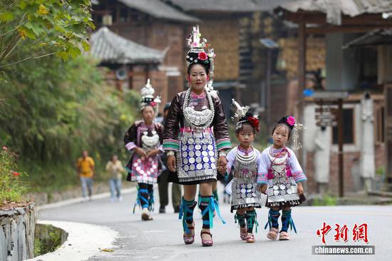 10月18日，身着盛装的黄岗村村民前往寨门迎接远方宾客。