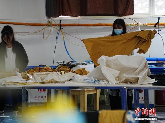 图为工人把做好的服装进行打包装袋。中新网记者 周燕玲 摄 图为工人把做好的服装进行打包装袋。中新网记者 周燕玲 摄
