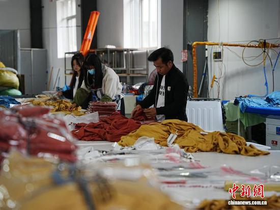 图为工人把做好的服装进行打包装袋。中新网记者 周燕玲 摄 图为工人把做好的服装进行打包装袋。中新网记者 周燕玲 摄