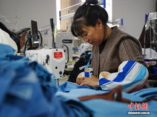 10月23日,位于贵州省毕节市赫章县金银山街道的就业帮扶车间,工人正在缝纫机前忙碌,赶制服装外贸订单。金银山街道是赫章县最大的易地扶贫搬迁安置点,共安置搬迁群众1.3万余人,就业帮扶车间的建立,让不少搬迁群众在“家门口”实现就业增收。记者 周燕玲 摄 10月23日,位于贵州省毕节市赫章县金银山街道的就业帮扶车间,工人正在缝纫机前忙碌,赶制服装外贸订单。金银山街道是赫章县最大的易地扶贫搬迁安置点,共安置搬迁群众1.3万余人,就业帮扶车间的建立,让不少搬迁群众在“家门口”实现就业增收。记者 周燕玲 摄
