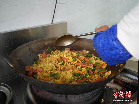图为员工在贵州省毕节市赫章县金银山街道的“岁月食堂”厨房烹饪西红柿炒鸡蛋。中新网记者 周燕玲 摄 图为员工在贵州省毕节市赫章县金银山街道的“岁月食堂”厨房烹饪西红柿炒鸡蛋。中新网记者 周燕玲 摄