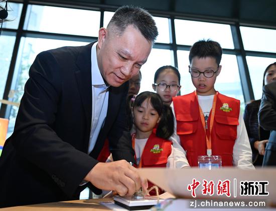图为：中国人寿寿险公司业务总监，浙江省分公司党委书记、总经理叶寿华在展览现场为小朋友加盖印章。中新社记者 王刚 摄