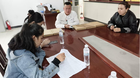 党建指导员梁芳在办公室指导企业人员准备材料。