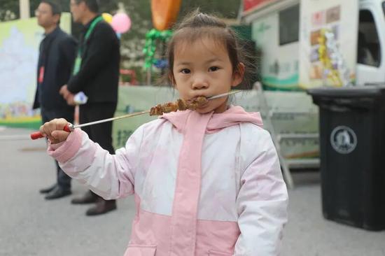 小朋友品尝烤羊肉串。阿的拉 摄