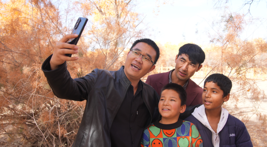 干部职工与结对亲戚同游胡杨林拍照留念。