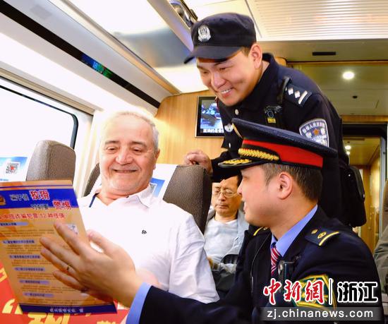 图为：乘警和列车长在车厢内向旅客宣传反诈知识。中新社发 贺瑞明 摄