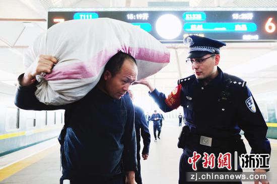 图为：乘警在站台帮助旅客托举行李。中新社发 贺瑞明 摄