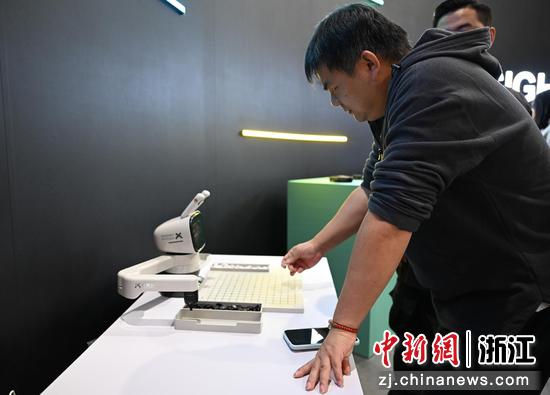 图为：下棋机器人吸引参观者体验。中新社记者 王刚 摄