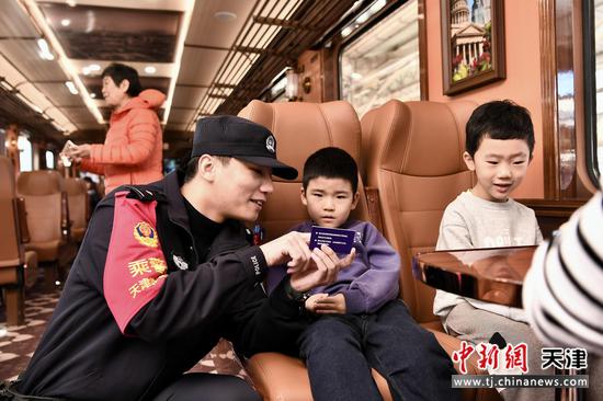图为“津旅时光号”列车乘警在车厢内向儿童宣传反诈安全常识。(北京铁路局天津公安处供图) 图为“津旅时光号”列车乘警在车厢内向儿童宣传反诈安全常识。(北京铁路局天津公安处供图)