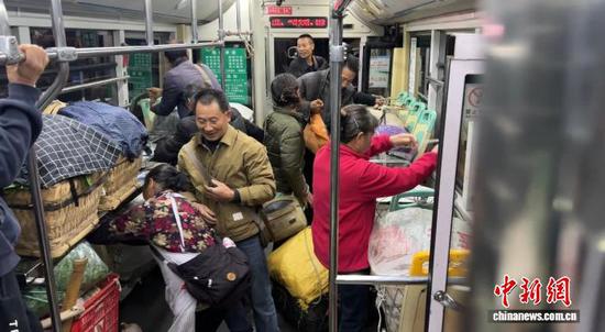 图为菜农将蔬菜等搬上公交车。 杨凯茗 摄 图为菜农将蔬菜等搬上公交车。 杨凯茗 摄