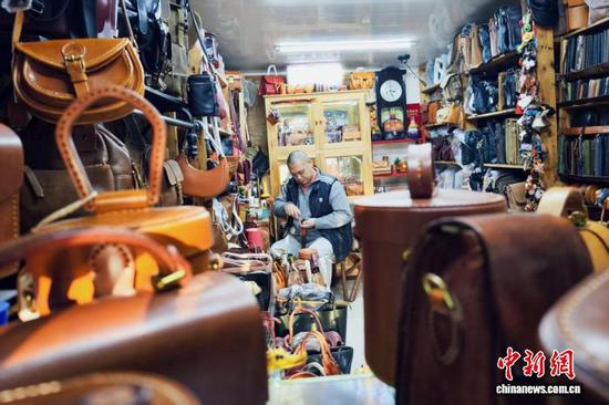 11月16日,在天津市河北区王串场街“修补巷”,皮具修复师李涛为顾客修复皮具。中新社记者 佟郁 摄 11月16日,在天津市河北区王串场街“修补巷”,皮具修复师李涛为顾客修复皮具。中新社记者 佟郁 摄