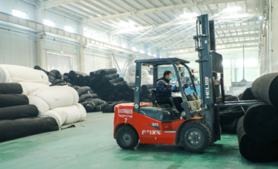 在阿拉尔市驰疆农业科技发展有限公司仓储车间，工人操作机械搬运生产大棚棉被的原材料。 冯佳乐 摄