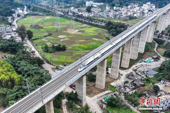 资料图：11月20日，贵州省兴义市，55933次运行试验列车行驶在盘兴高铁清水河镇特大桥上。(无人机照片) 中新社记者 瞿宏伦 摄