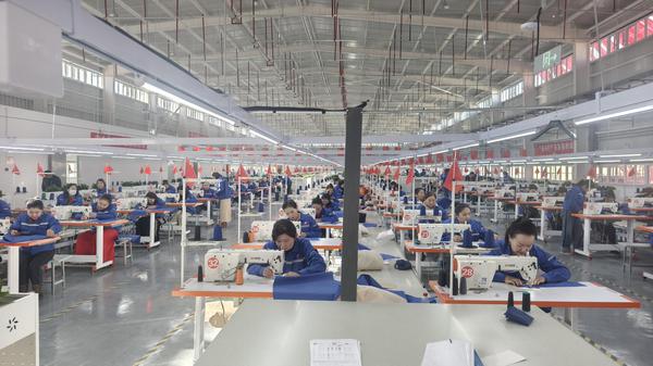 图为：工人们生产线上加工服装