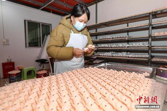 图为一位工人在检查唐娃娃头部。中新社记者 瞿宏伦 摄