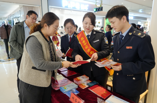 昌吉市税务局税务干部走进辖区商圈，通过普法宣讲、发放资料等形式，向商户和群众普及宪法和税法知识。张雨薇 摄e