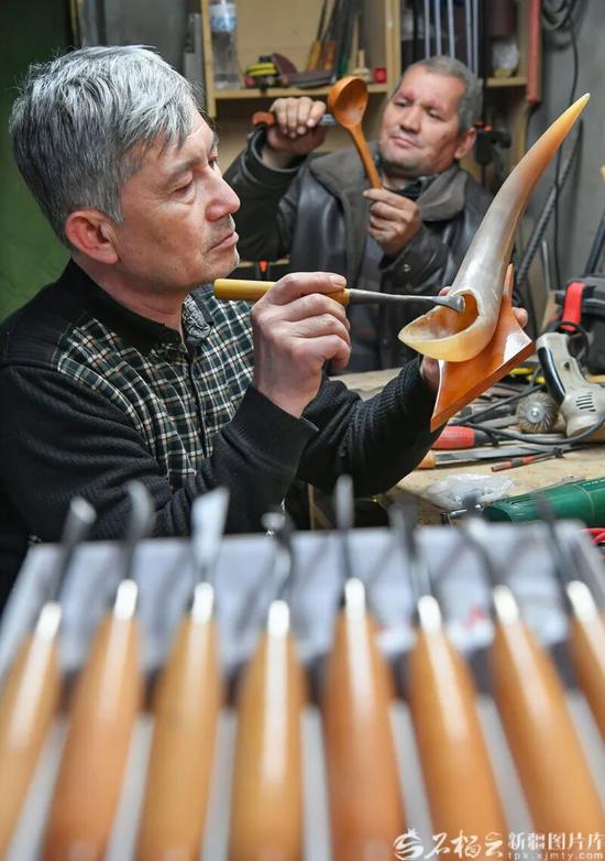 12月1日，艾尼江在工作室和徒弟一起制作牦牛角雕刻作品。